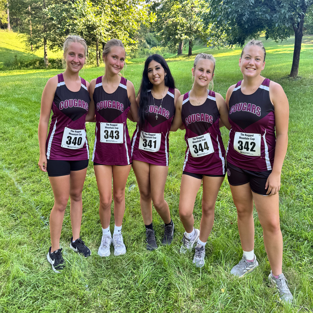 5 track runners lined up for a picture before their meet standing in the grass