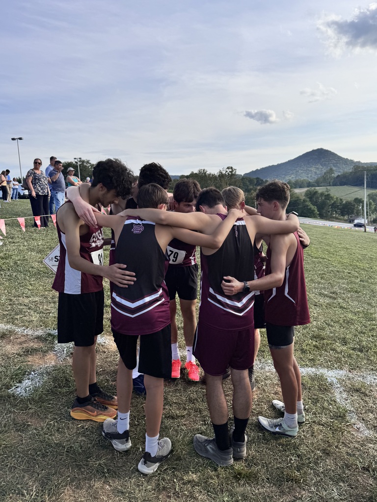 group of male track runners huddled together before their meet
