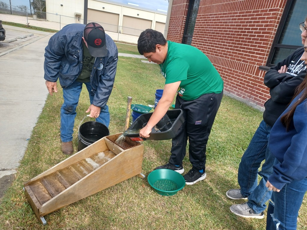 A student pours water into a "rocker" device used in gold mining.