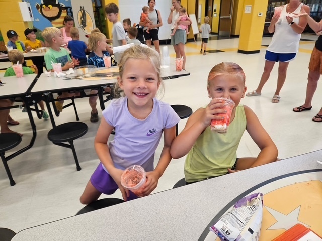 Two females students smiling at camera holding their dessert. 