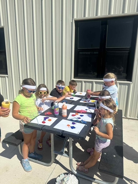 Students outside at picnic table painting