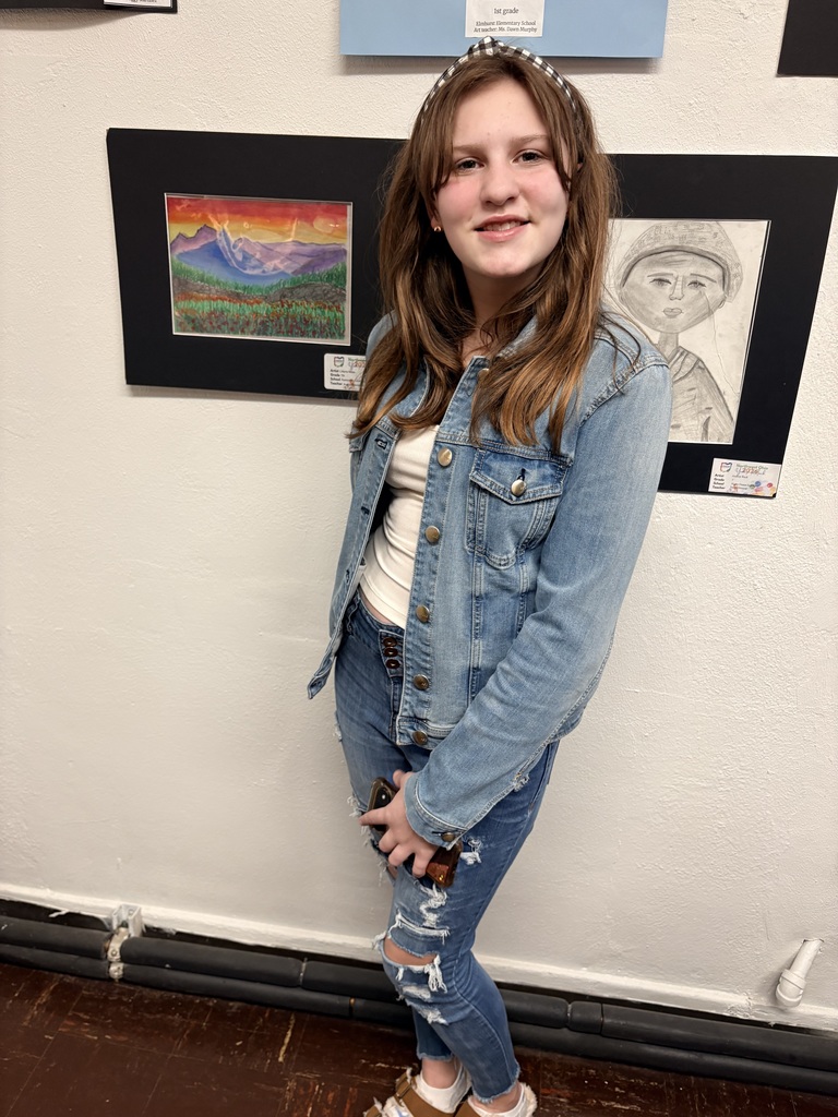 Liliana Miles is pictured standing beside her brightly colored oil pastel landscape drawing.