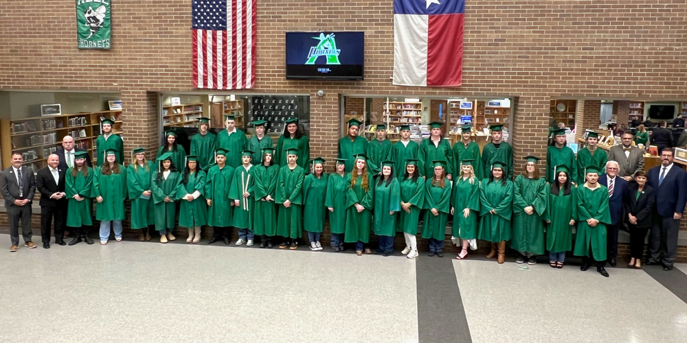 group of Hornet Academy graduates standing under American and TX flags