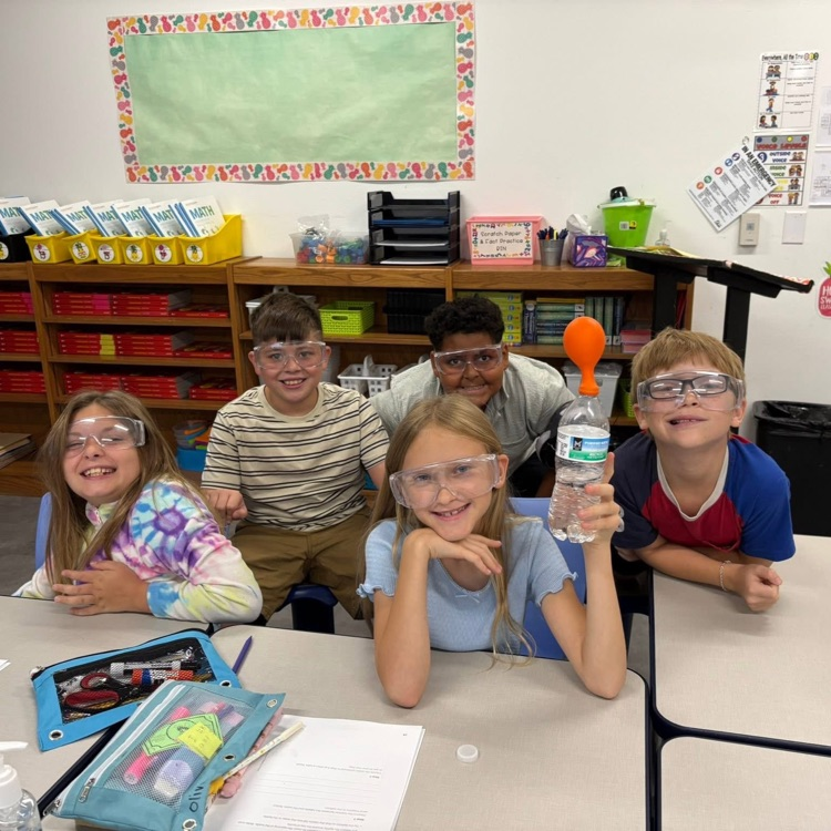 group up students wearing science goggles holding balloons
