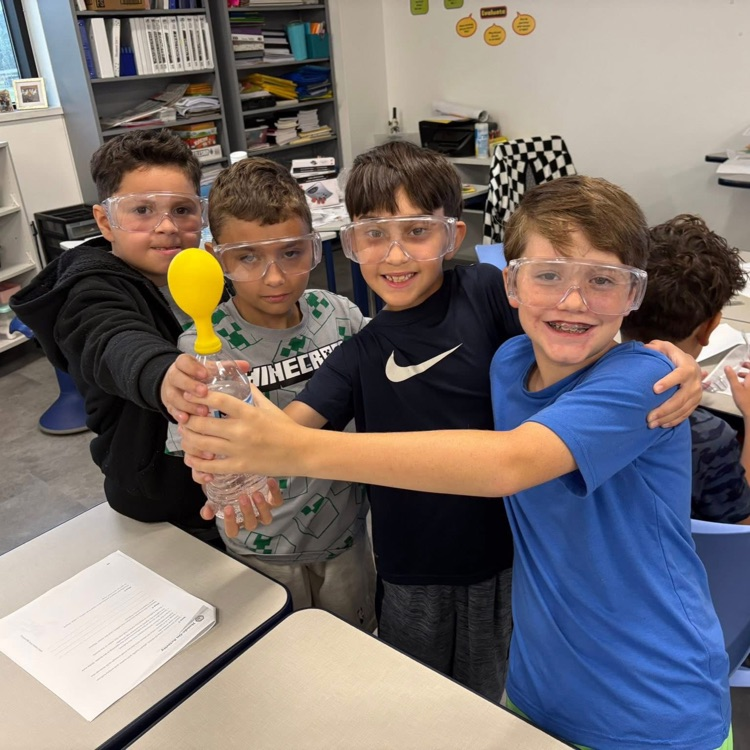 group up students wearing science goggles holding balloons