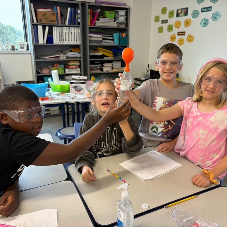 group up students wearing science goggles holding balloons