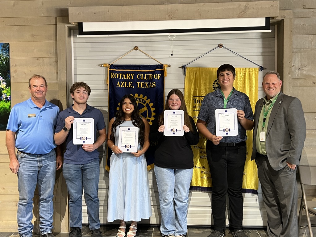 group of students holding certificates, standing in front of Rotary Club banners