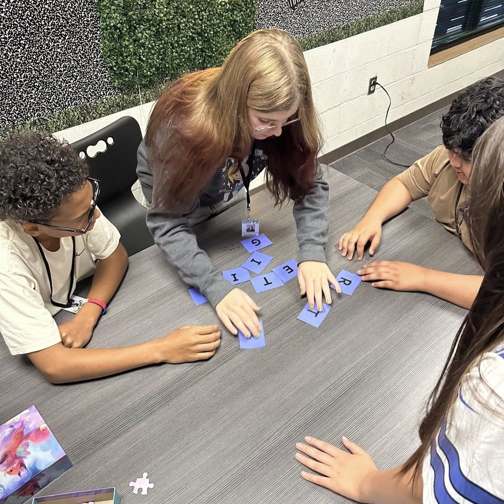 group of students at table working with lettered puzzle pieces