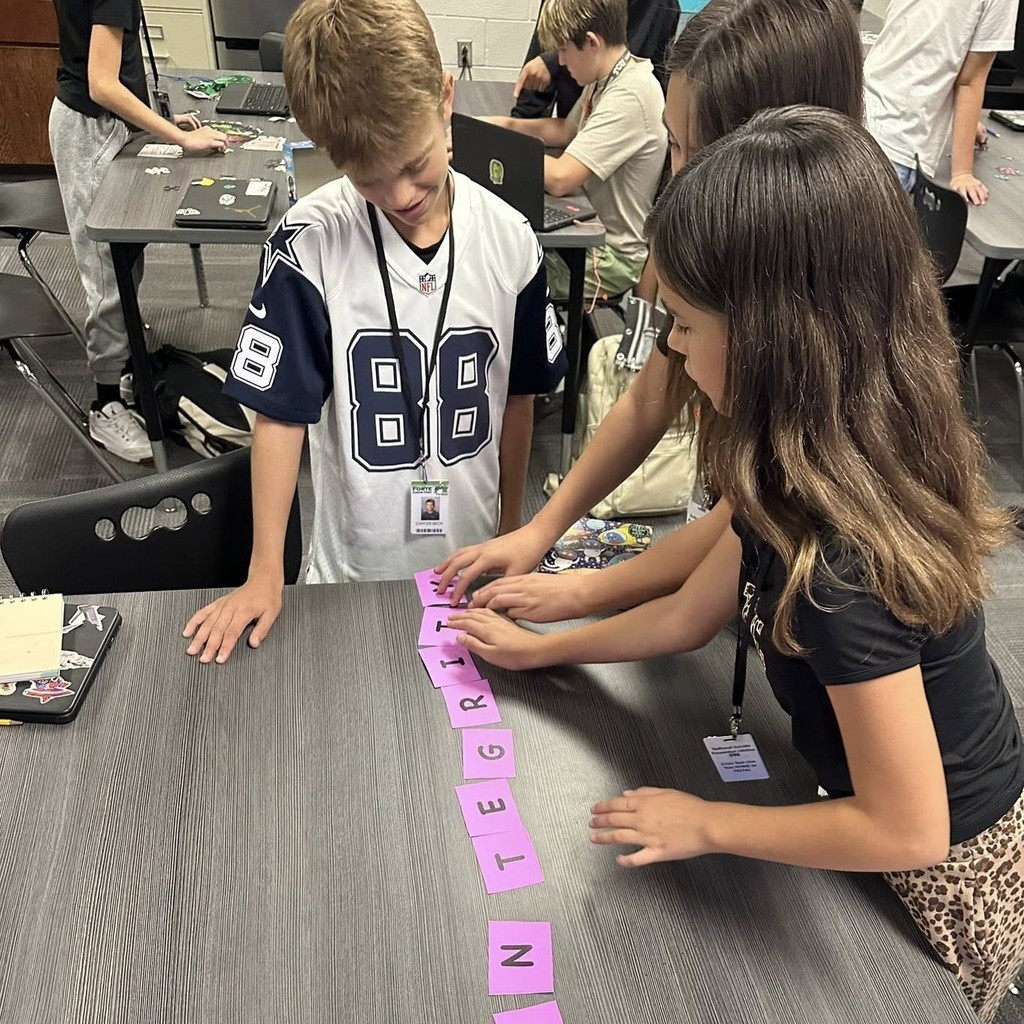 group of students at table working with lettered puzzle pieces