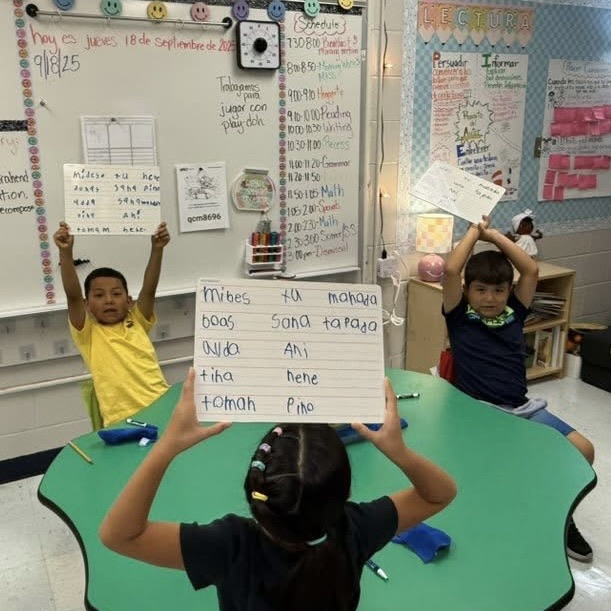 elementary students holding up big papers with writing on them 