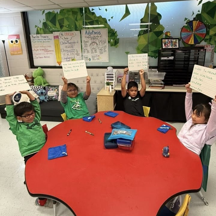 elementary students holding up big papers with writing on them 