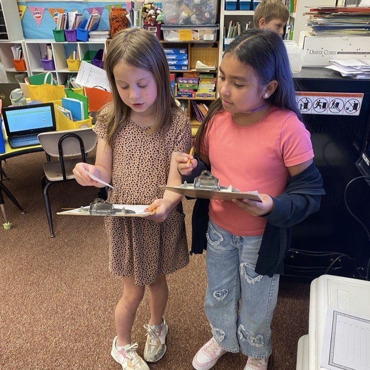 two elementary girls holding clipboards