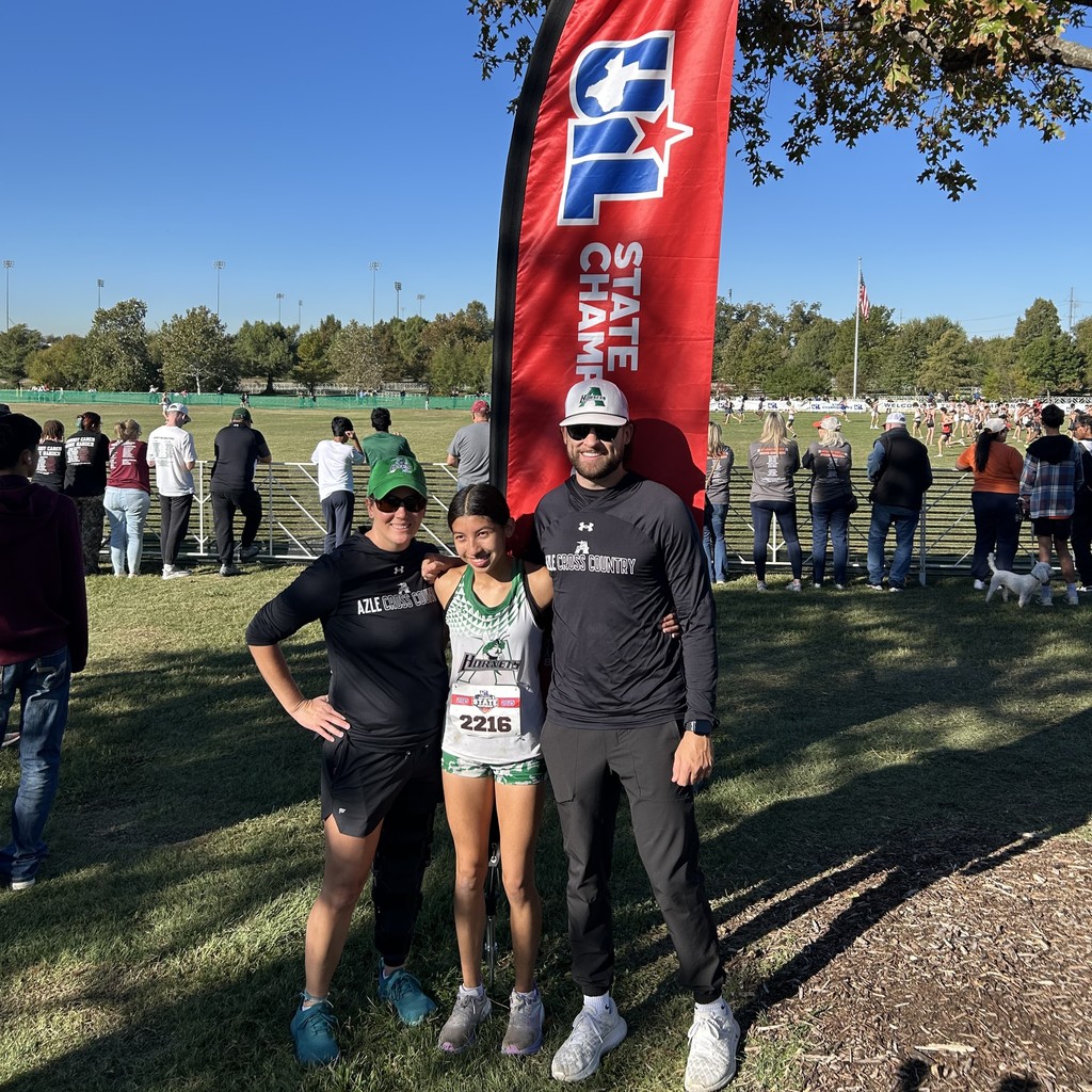 AHS Cross Country girl - Jazmin Neri standing with coaches in front of UIL State Banner