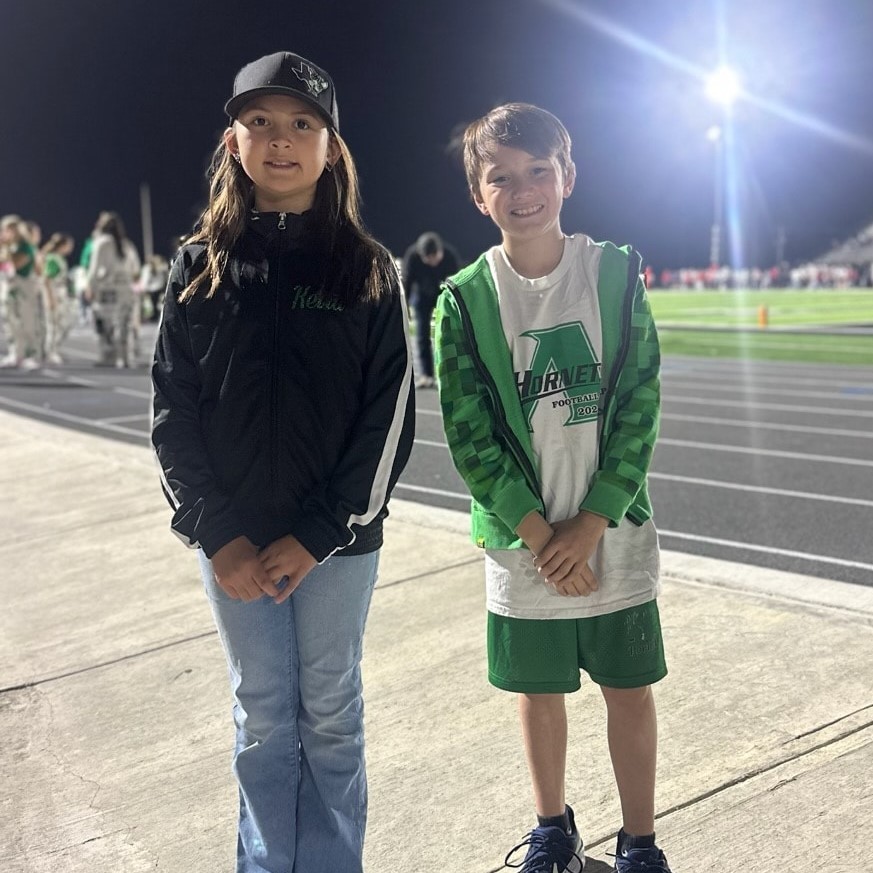 two students standing near track at football field