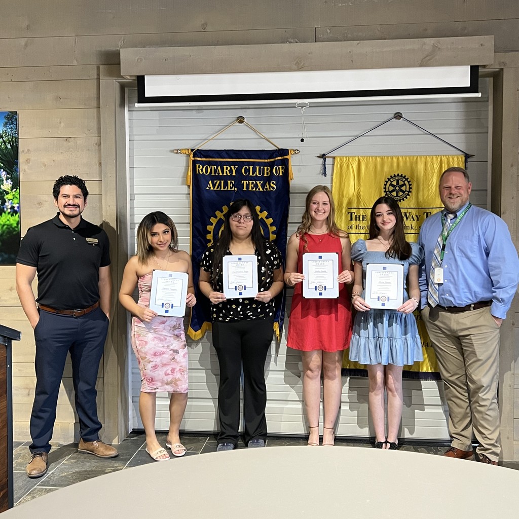 group of students holding certificates, standing in front of Rotary Club banners