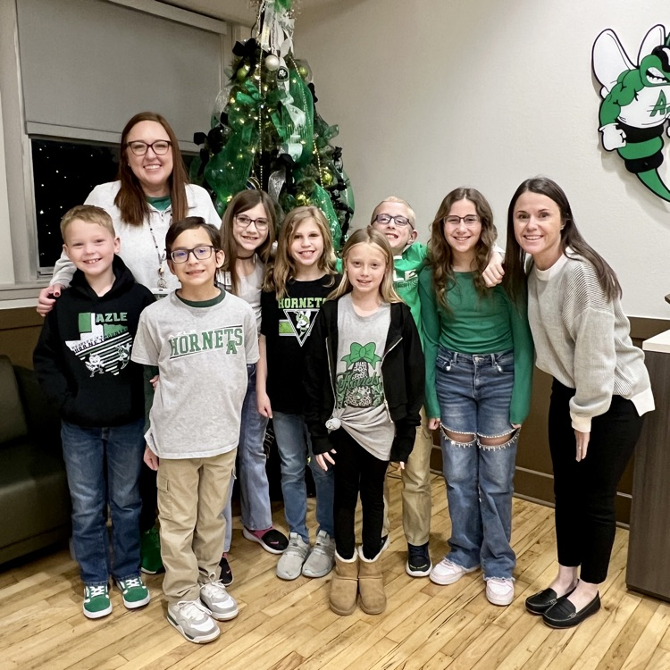 group of students standing in front of Christmas tree