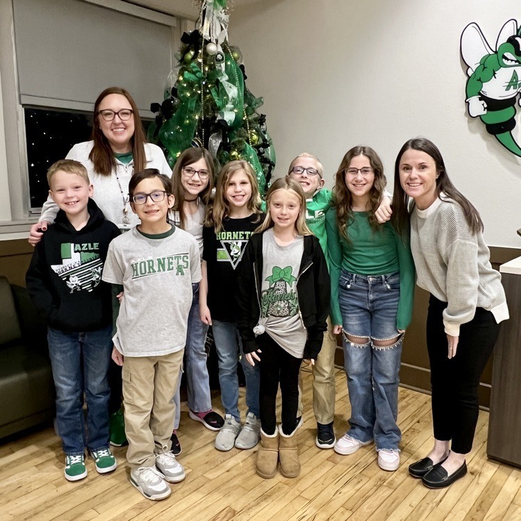 group of students standing in front of Christmas tree