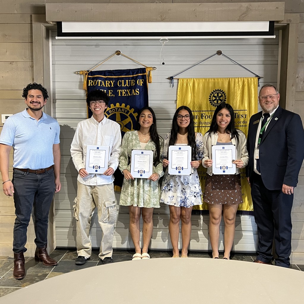 group of students holding certificates standing in front of Rotary Club banners