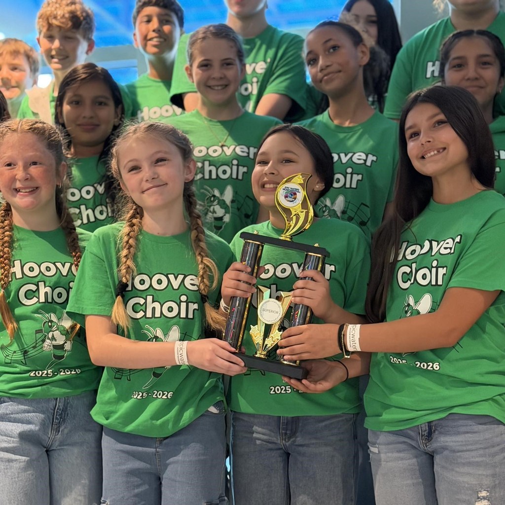group of students wearing green tshirts and holding trophy