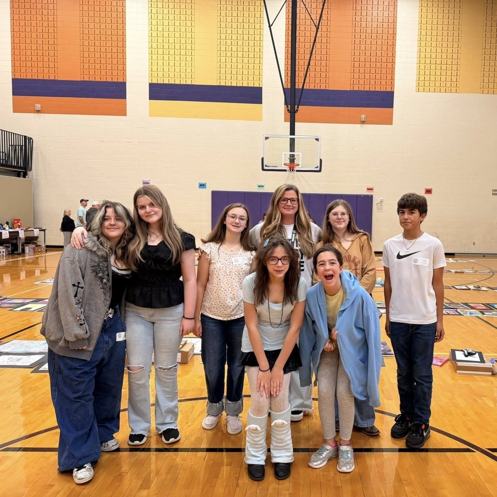 group of students standing in gym with artwork on display in the background