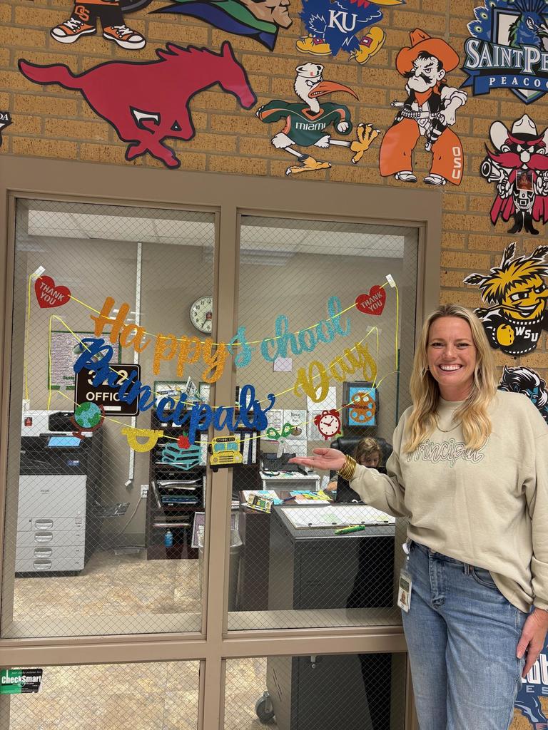 Dr. Norris smiling next to a sign that says "Happy School Principals' Day!"