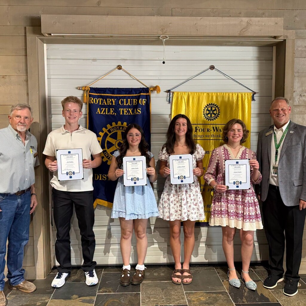 group of high school students holding certificates standing in front of Rotary Club banners