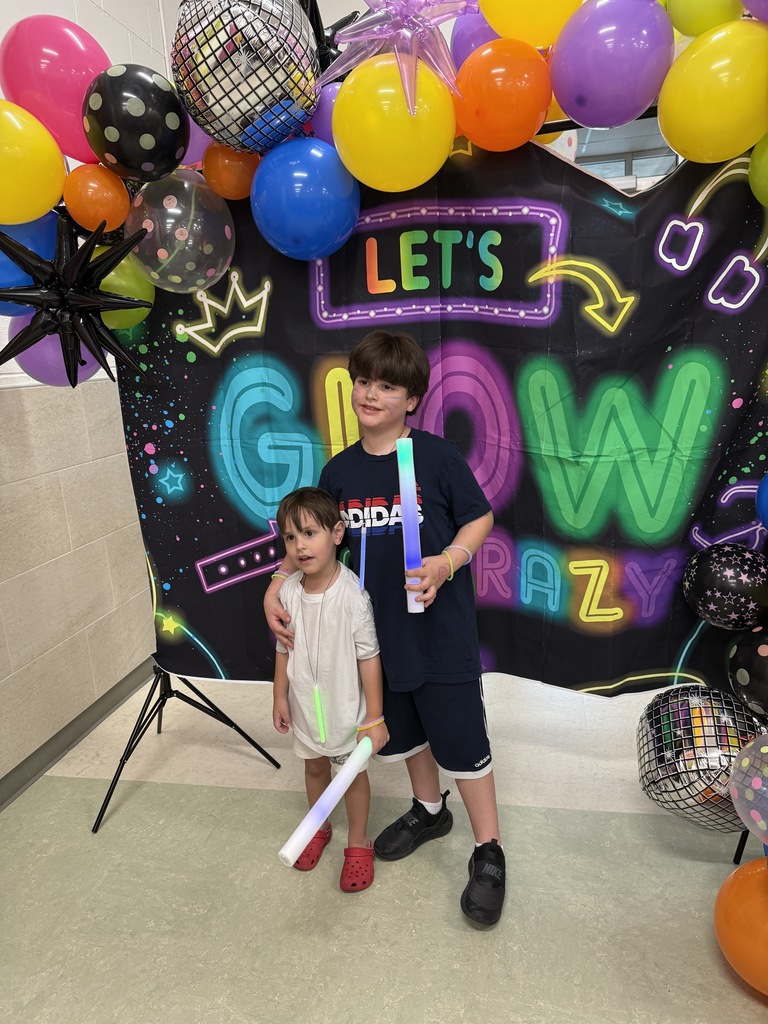 Photo of students in front of Let's GLOW Crazy backdrop