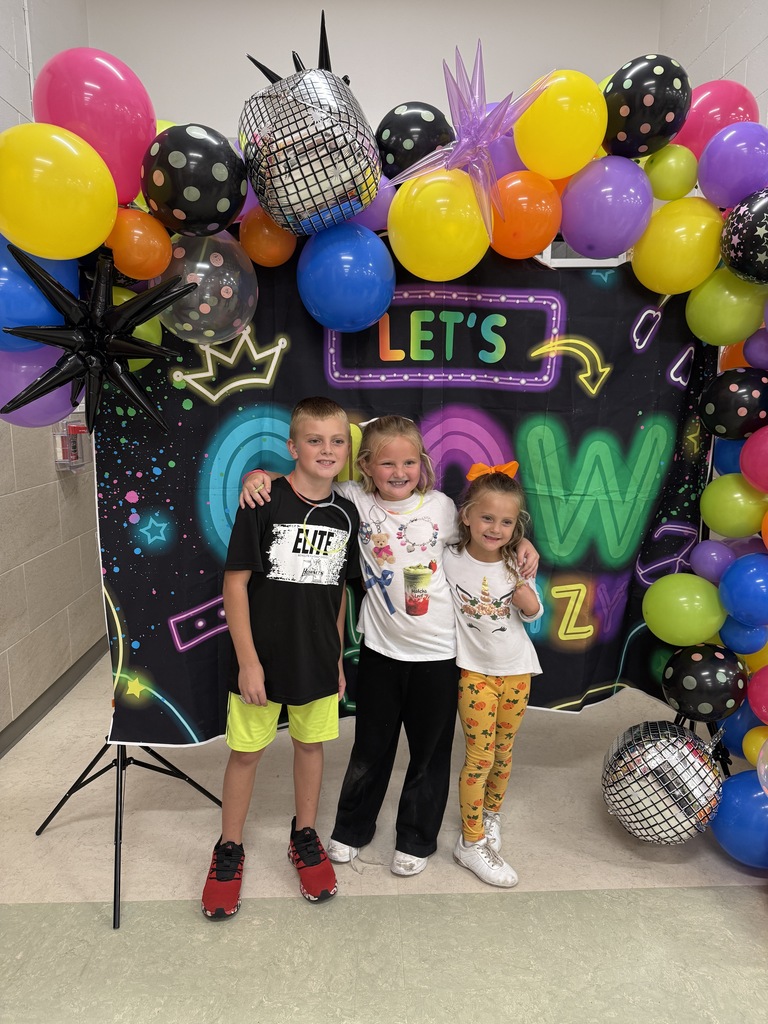 Photo of students in front of Let's GLOW Crazy backdrop