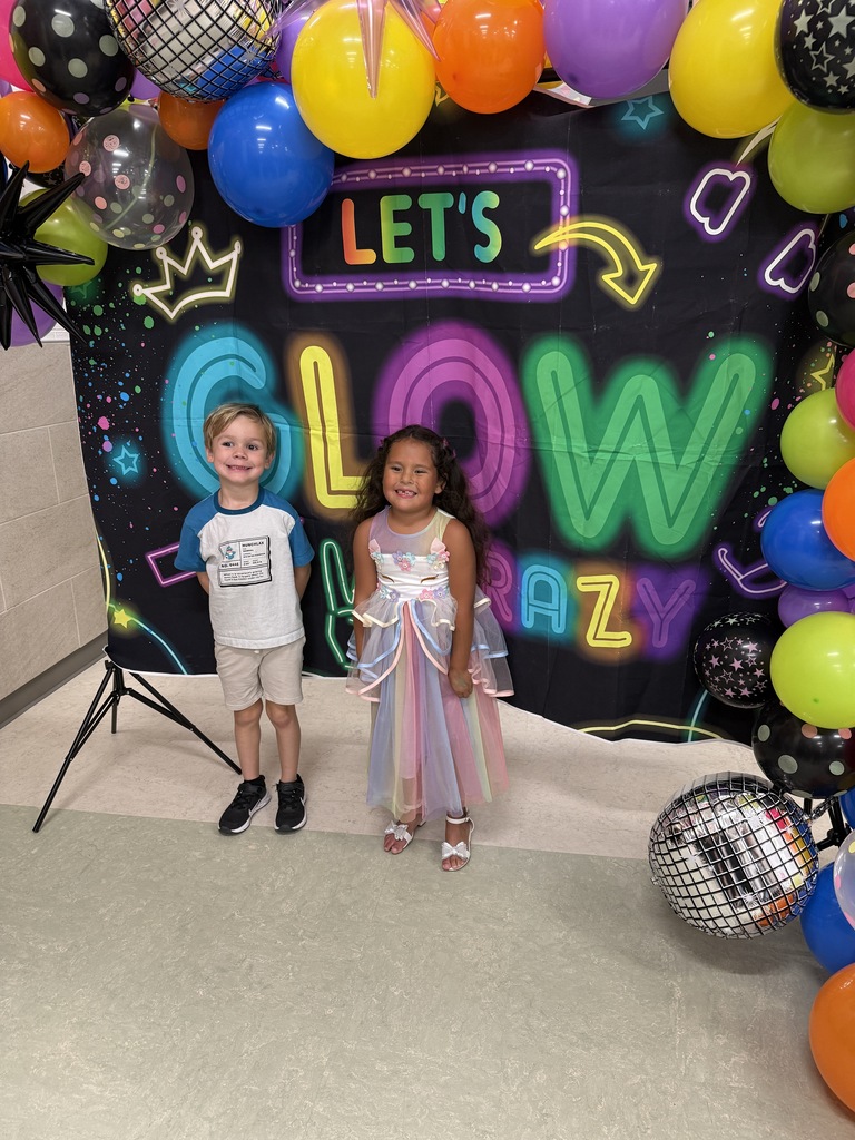 Photo of students in front of Let's GLOW Crazy backdrop