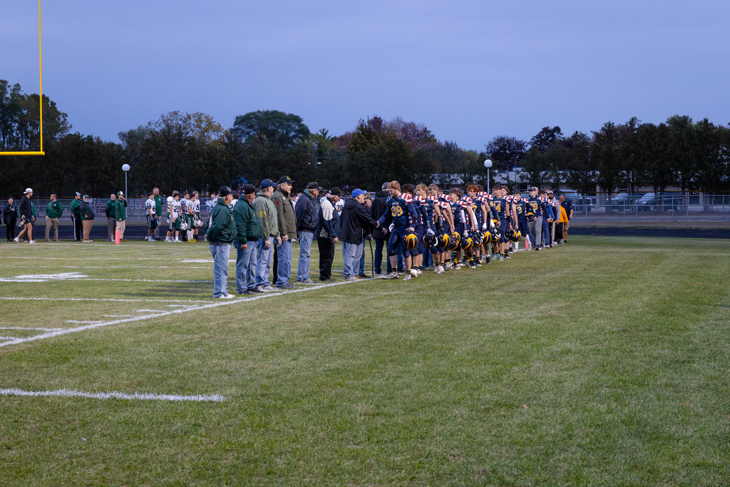 Community Veterans and Bad Axe Varsity Football Team come together under the football lights to shake each others' hands.