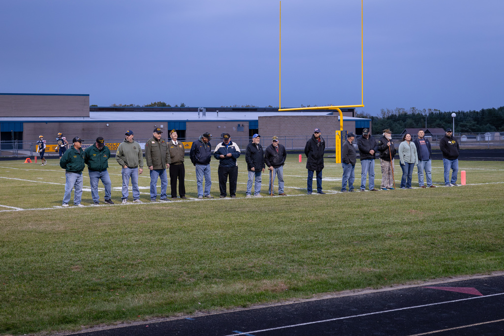 Community Veterans and Bad Axe Varsity Football Team come together under the football lights to shake each others' hands.