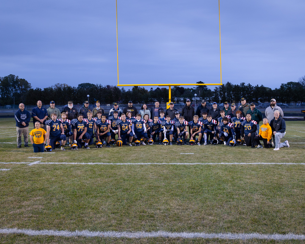 Community Veterans and Bad Axe Varsity Football Team come together under the football lights to shake each others' hands.