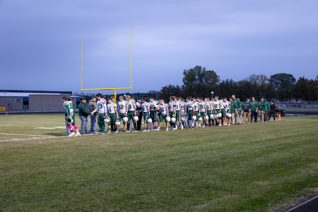 Community Veterans and Bad Axe Varsity Football Team come together under the football lights to shake each others' hands.