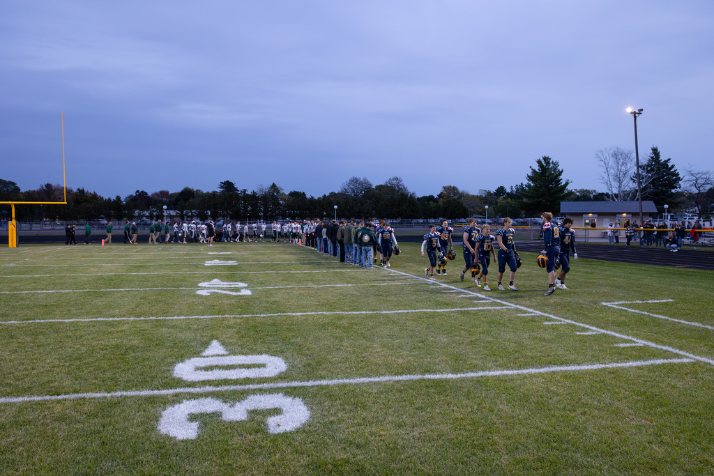 Community Veterans and Bad Axe Varsity Football Team come together under the football lights to shake each others' hands.