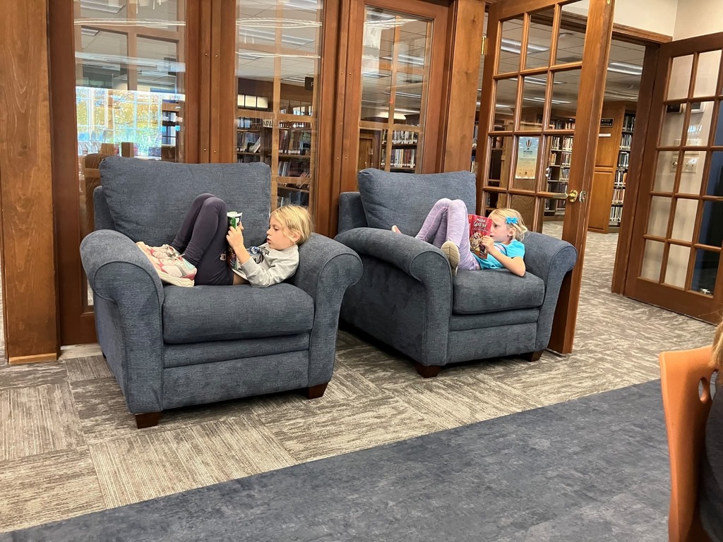 two students reading in lounge chairs