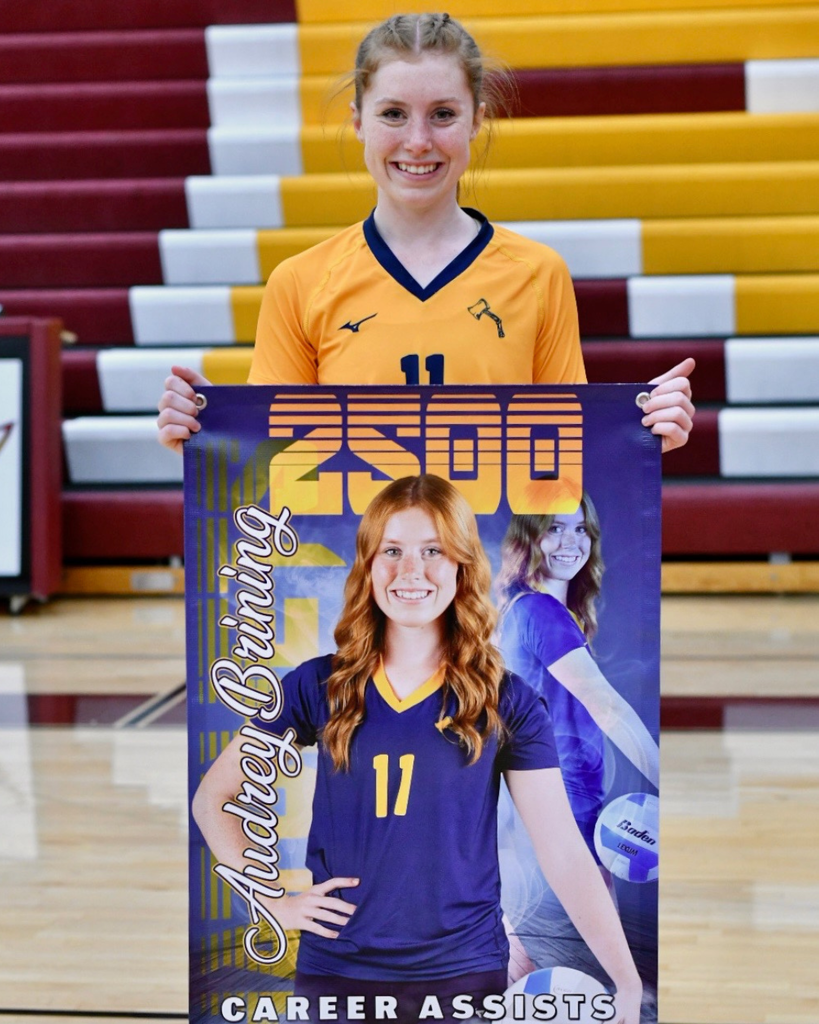 Audrey Brining with a yellow jersey on holding a poster that says her name and "2,500"