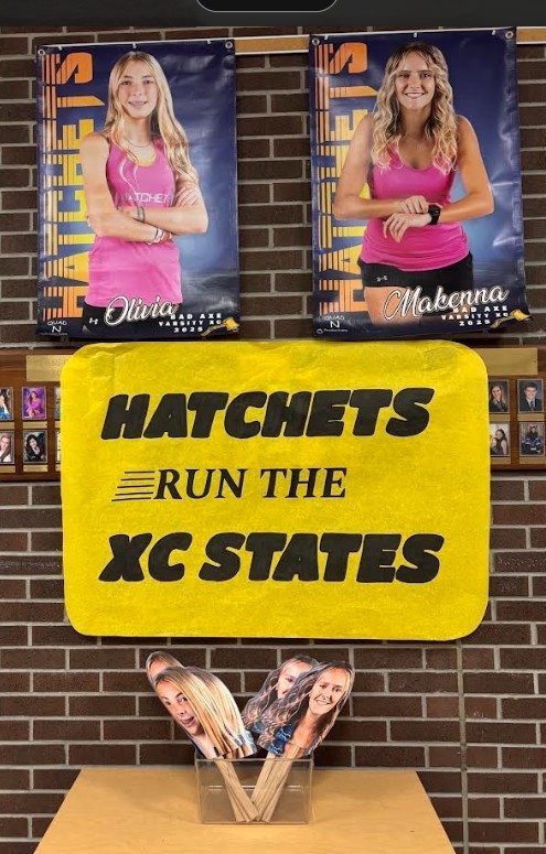 Yellow sign that says, "Hatchets run Cross Country States" with little posters with the students faces on them.