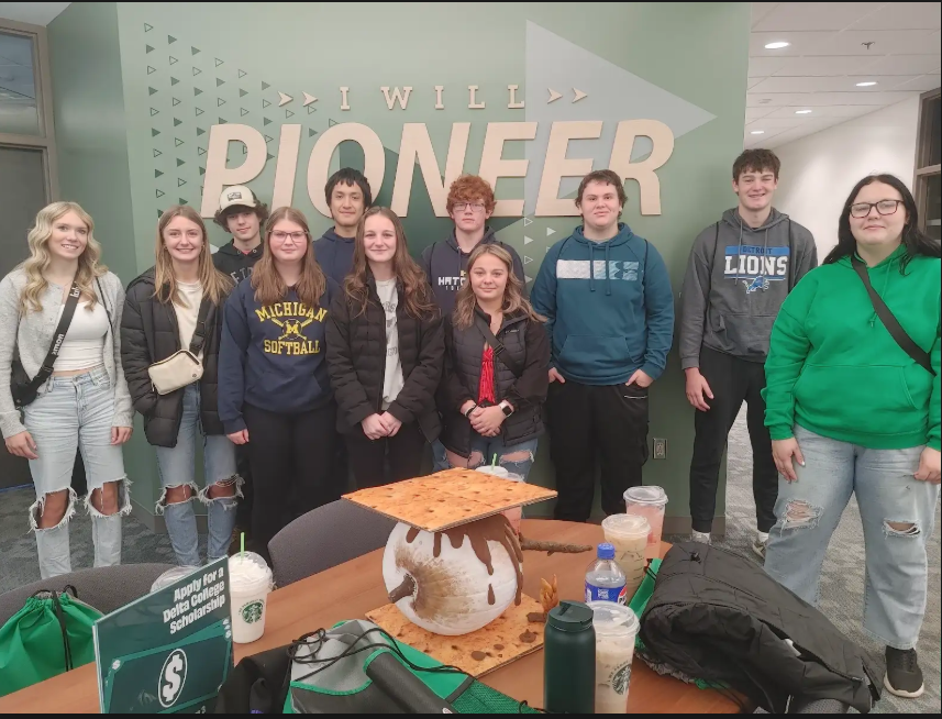 Bad Axe High School Students standing in front of a sign at Delta College that says, "I Will Pioneer"