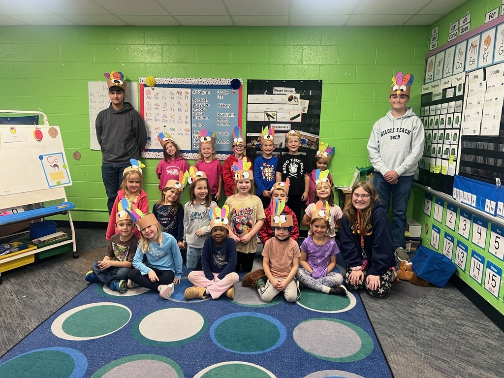 Mrs. Fischer's Kindergarten class with turkey hats standing next to High School FFA students.