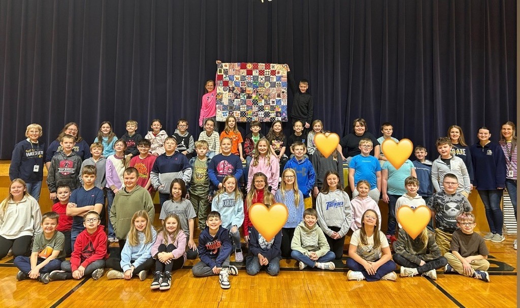 Mrs. Wessels 4th grade class standing with their hand-made quilt.