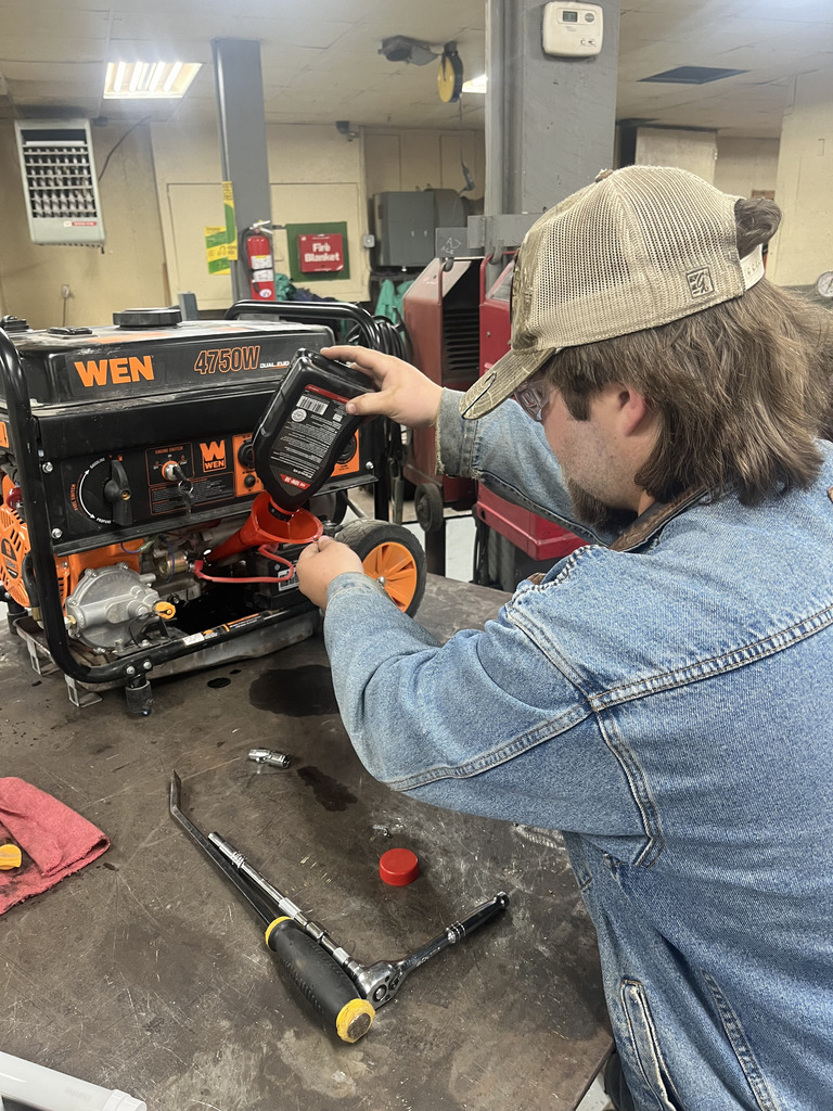 Noah Fyffe learning to change oil this week on another generator for a local resident.