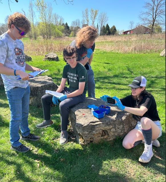 Students working on worksheets by the lake.