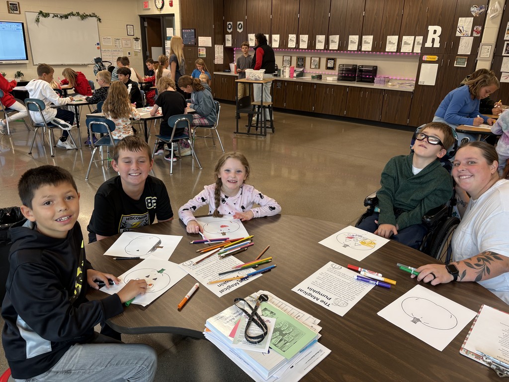 Students and a teacher smiling at the table in the classroom