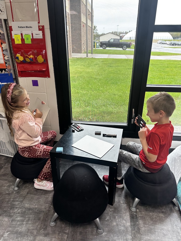 Two students working on math by the window of their classroom