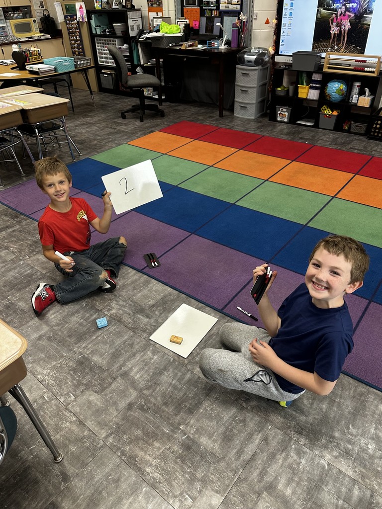 Two boys holding up math activity and smiling