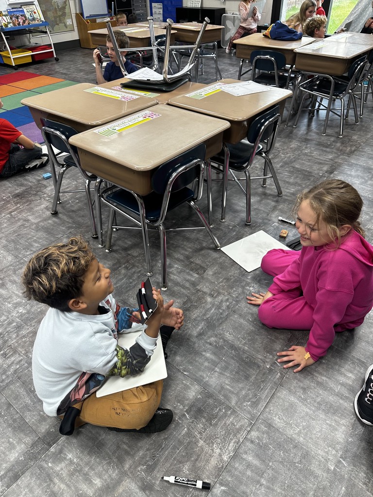 Two students sitting on the floor doing their math homework.