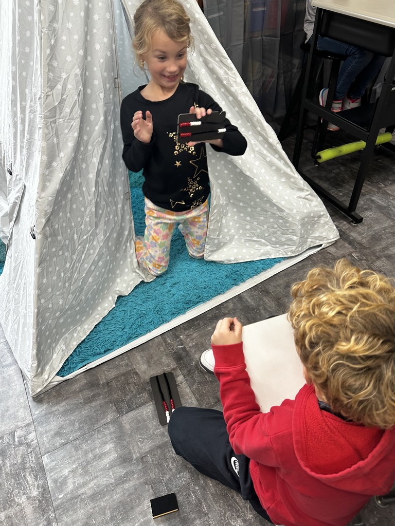 Two students in a tent working on math.