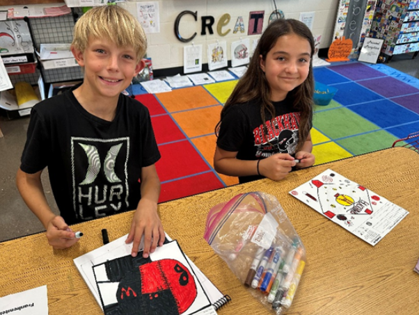 Two students smiling with their projects