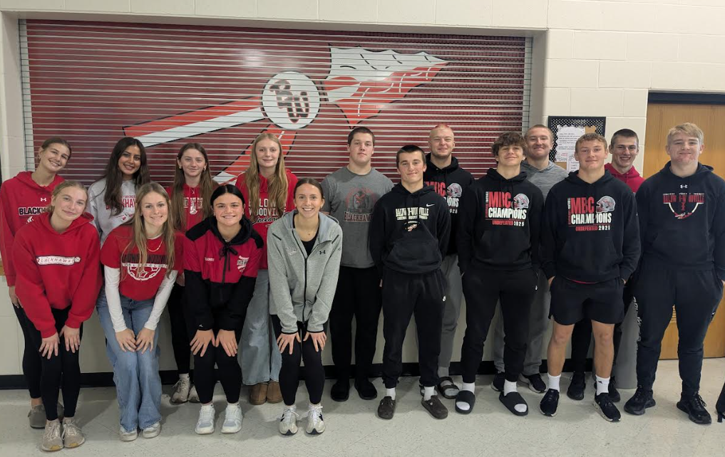 The committee of students standing and smiling in the high school commons.