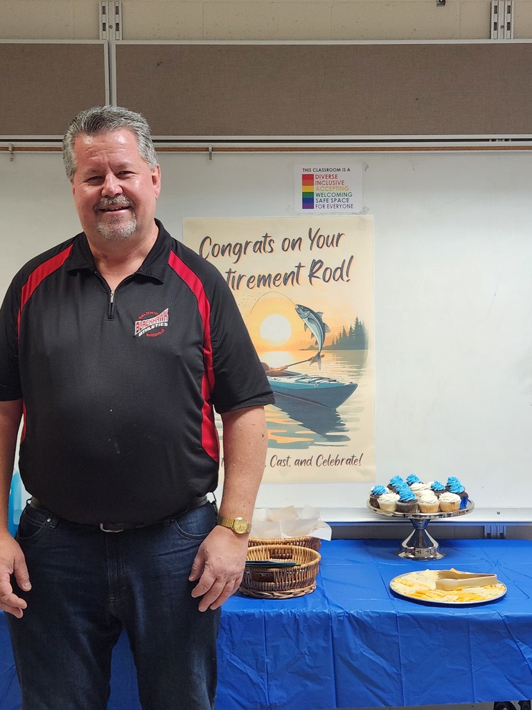 A picture of Rod smiling with his retirement poster and cupcakes.